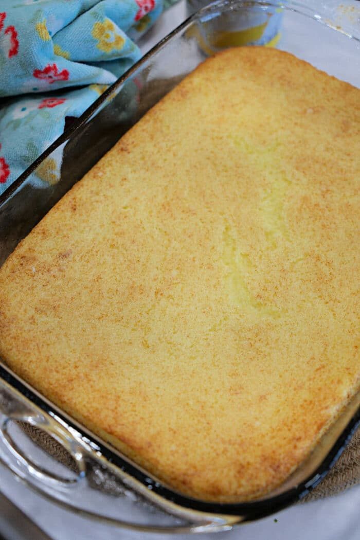 A golden-brown baked cornbread in a glass dish next to a colorful towel, solid for pairing with your favorite carnivore meatloaf.