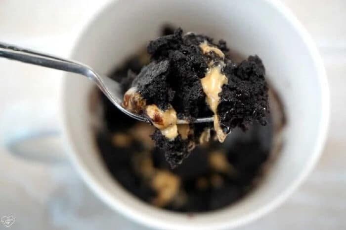 Spoonful of chocolate cake and peanut butter being lifted from a white mug, showing how easy it is to make a brownie in a mug for a quick, good treat.