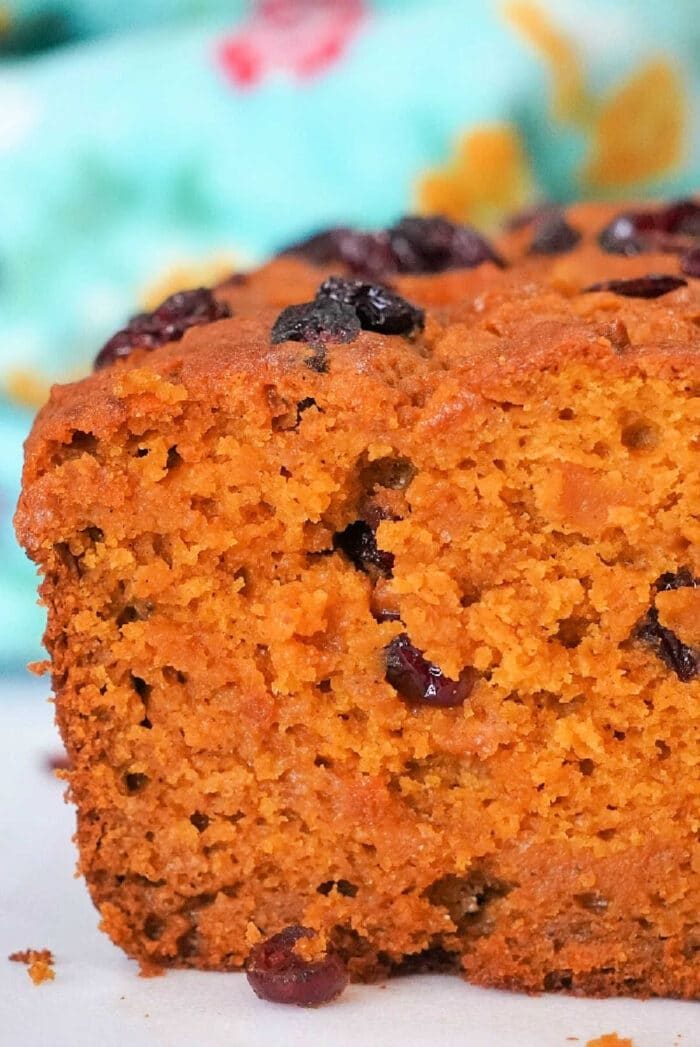 Close-up of a slice of easy pumpkin bread, against a colorful background.