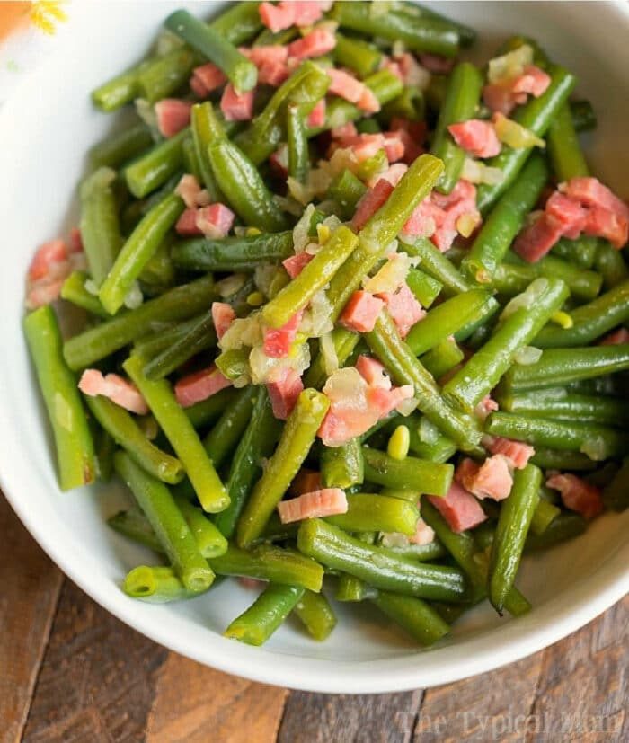 A bowl of sautéed green beans, perfected in the Ninja Foodi, mixed with diced bacon and onions.