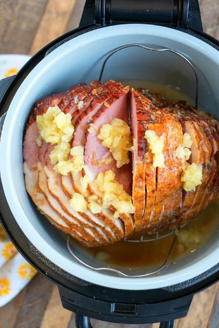 A spiral-cut ham with pineapple chunks and juice in a Ninja Foodi, ready to be cooked to perfection.