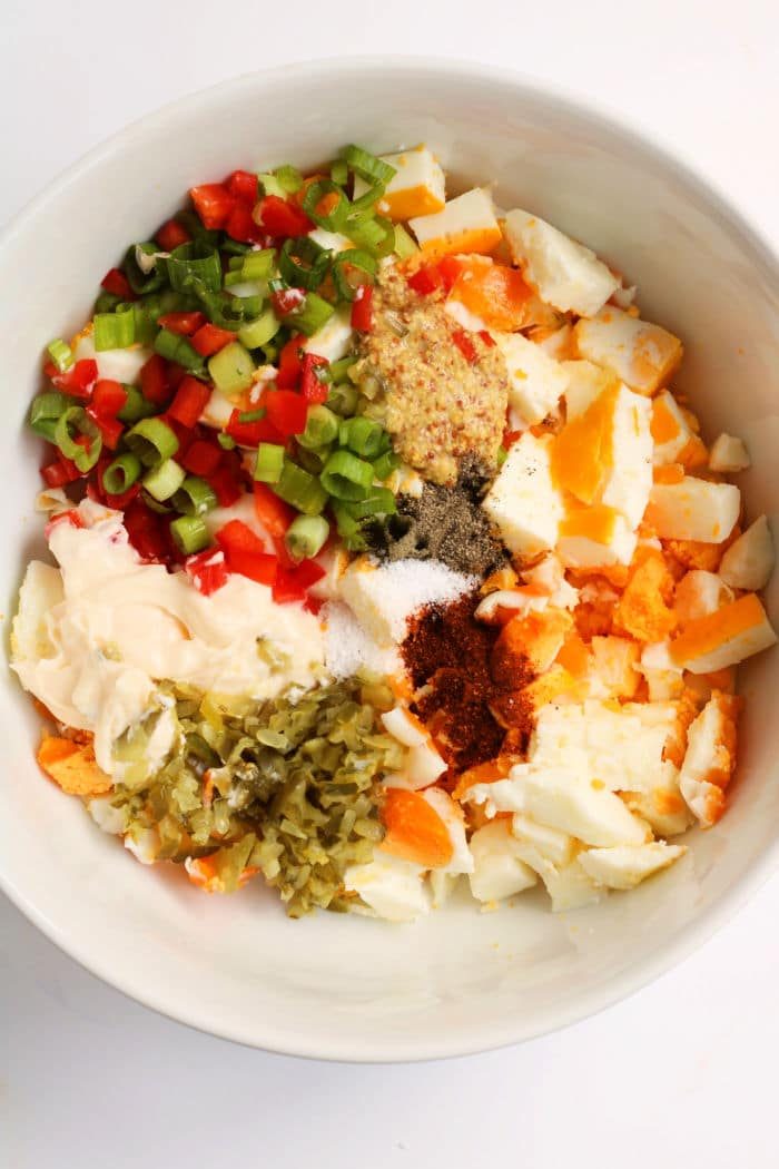 Bowl of chopped no peel hard boiled eggs, peppers, green onions, mayonnaise, mustard, and spices, ready to be mixed.