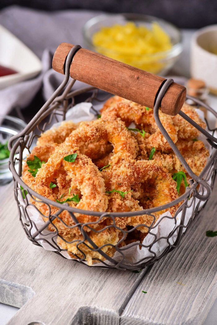 A basket of crispy breaded calamari, reminiscent of Olive Garden's calamari, is garnished with parsley on a wooden table.