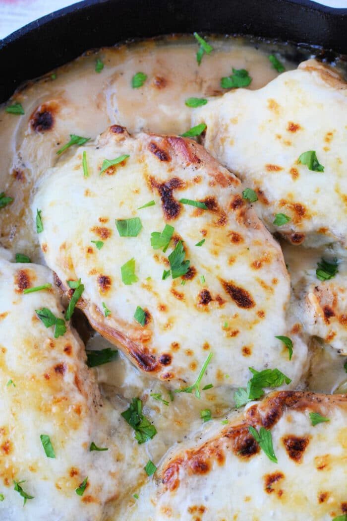 Chicken breasts topped with melted cheese and garnished with chopped parsley in a skillet, solid for anyone who loves hearty dishes like Baked Pork Chops.