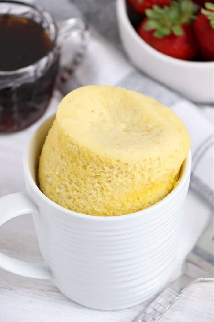 pancake in a white cup, paired perfectly with a bowl of strawberries and a steaming cup of coffee, brings to mind the comfort of a pancake in a mug.
