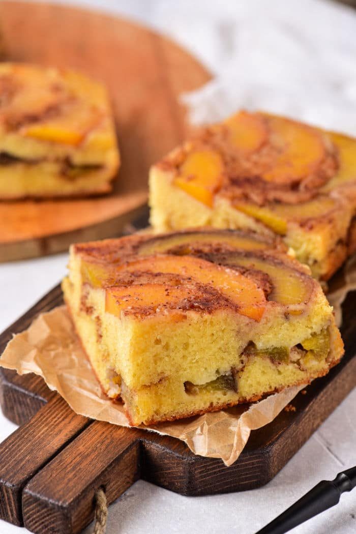 Slices of spiced peach upside-down cake rest invitingly on a wooden board.