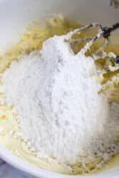 A mixer delicately blends flour and butter in a white bowl, setting the stage for the creation of a delightful dessert topped with creamy peppermint frosting.