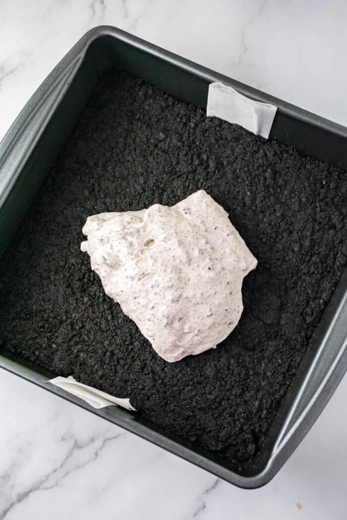 A baking pan with a oreo base and a mound of creamy Philadelphia Cheesecake Bars mixture on top.