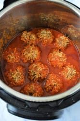 An Instant Pot filled with porcupine meatballs in a rich red tomato sauce. The meatballs, perfectly cooked, are partially submerged, allowing a glimpse of the seasoned sides and bottom of the cooker.