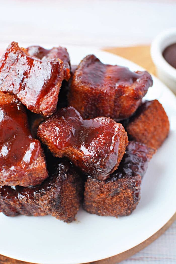 Plate of glazed, saucy pork belly burnt ends arranged in a pile on a white plate—an irresistible recipe for smoked perfection.