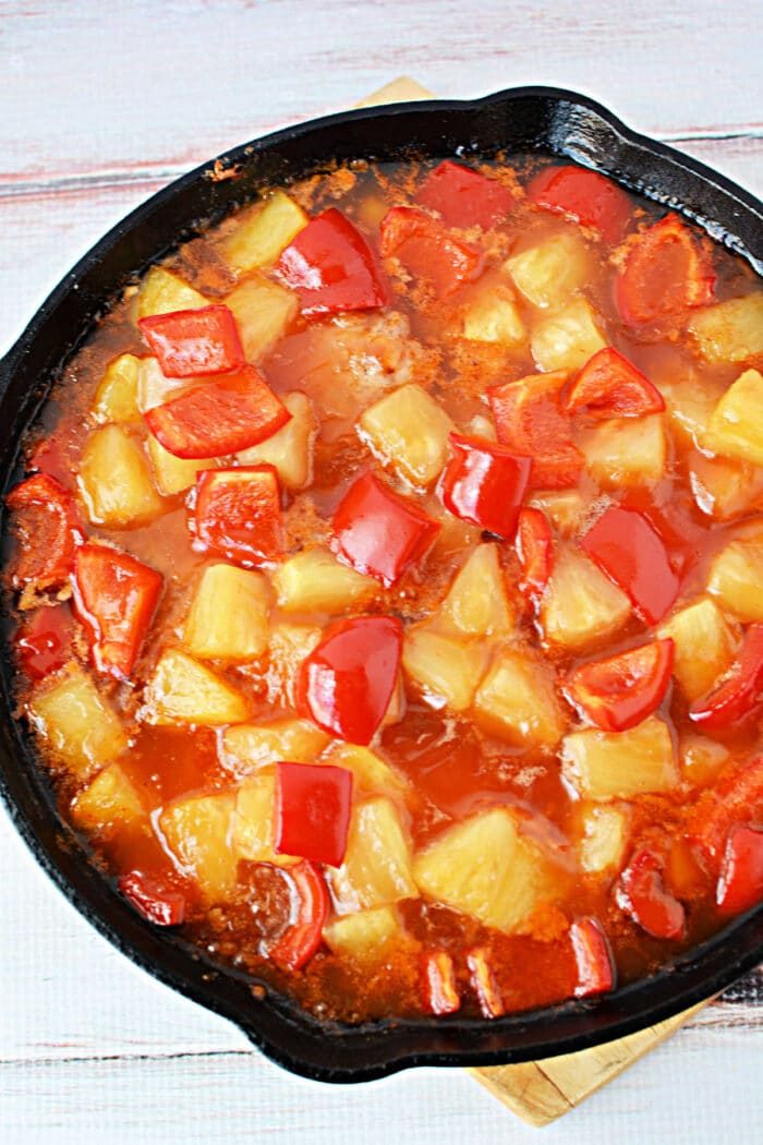 A skillet filled with sweet and sour sauce, pineapple chunks, red bell peppers, and tender pork chops—solid for trying new pork chop recipes.