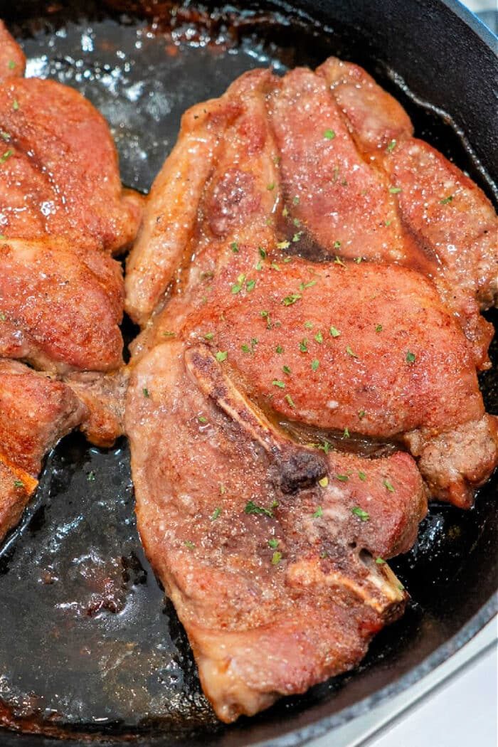 Seared flavorful Pork Shoulder Steak, coated with seasoning and sizzling in a cast iron skillet.