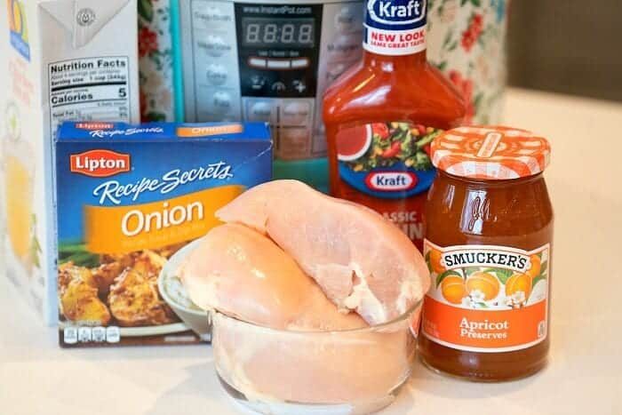 Raw chicken breasts in a bowl with onion soup mix, French dressing, apricot preserves, and an Instant Pot behind—solid for making pressure cooker apricot chicken.