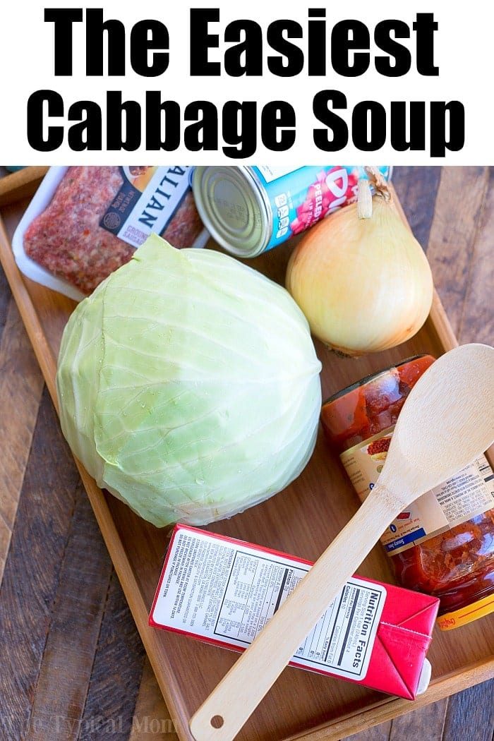 Tray with cabbage, onion, ground meat, canned tomatoes, tomato sauce, soup broth, and a wooden spoon—solid ingredients to make a hearty pressure cooker cabbage soup.