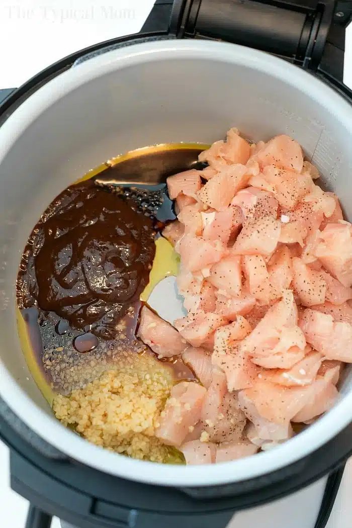 Diced raw chicken, sauce, oil, and minced garlic in an Instant Pot before cooking make the solid base for pressure cooker cashew chicken.