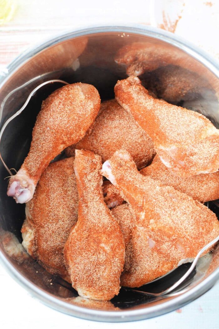Chicken drumsticks, expertly seasoned and nestled in a metal pot, are transformed into succulent fried chicken using the magic of a pressure cooker.