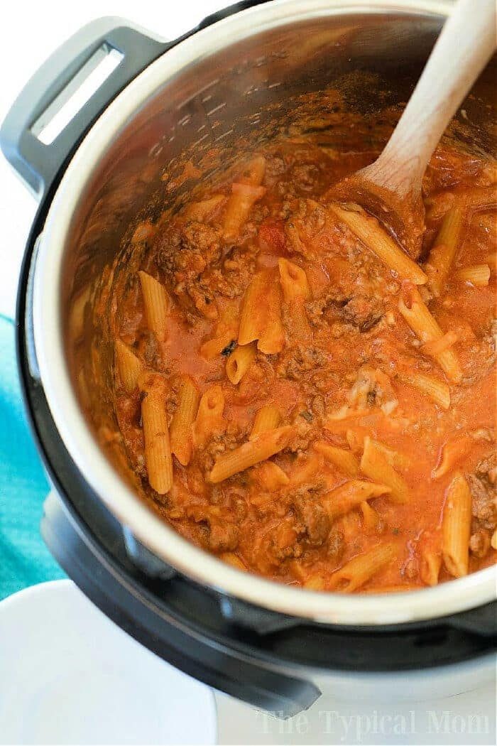 Pasta with meat sauce being stirred with a wooden spoon inside an Instant Pot for a good pressure cooker lasagna casserole.