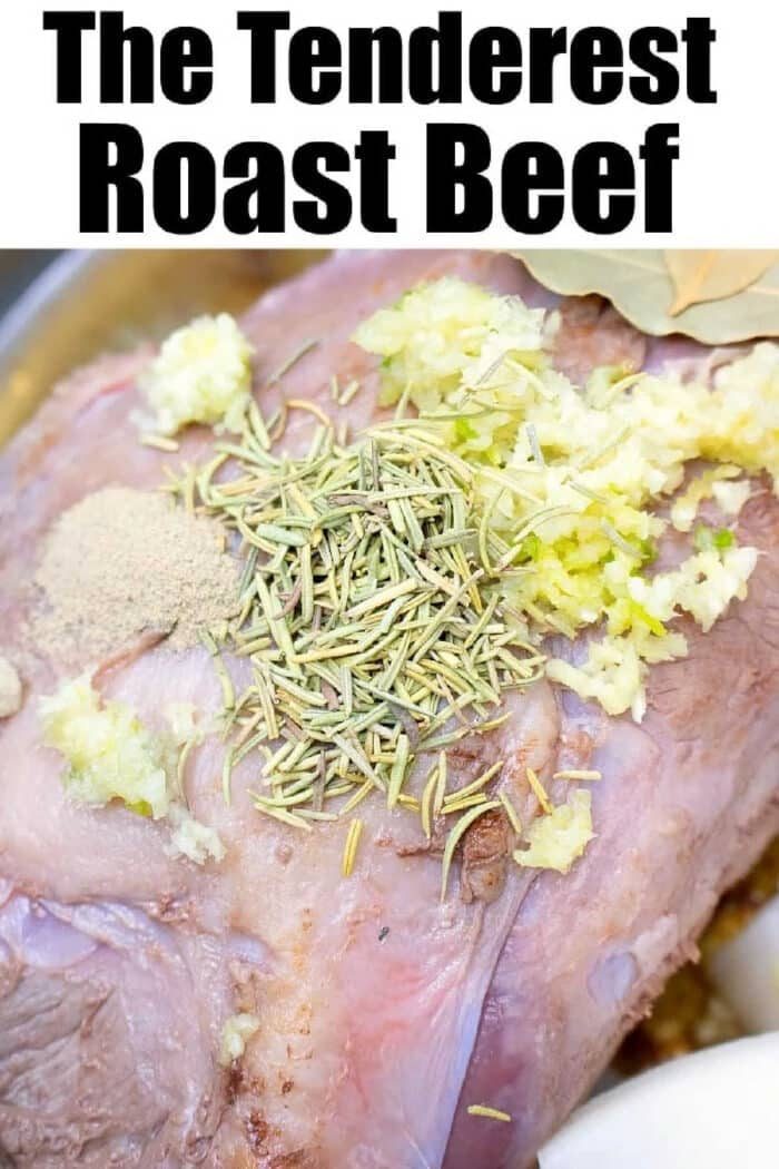 A raw pressure cooker roast beef topped with minced garlic, rosemary, and spices, ready to be cooked.