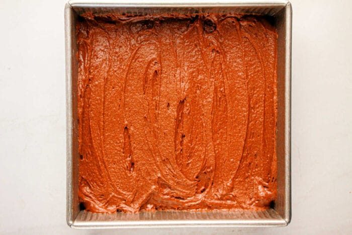 Protein-packed brownie batter spread evenly in a square metal baking pan.
