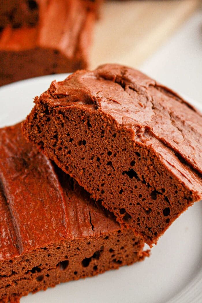 Close-up of two decadent slices of protein brownies on a white plate.