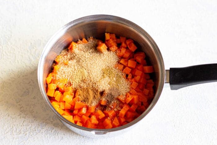 Chopped pumpkin topped with brown sugar and cinnamon meld harmoniously in a saucepan, creating a delightful blend reminiscent of pumpkin jam.