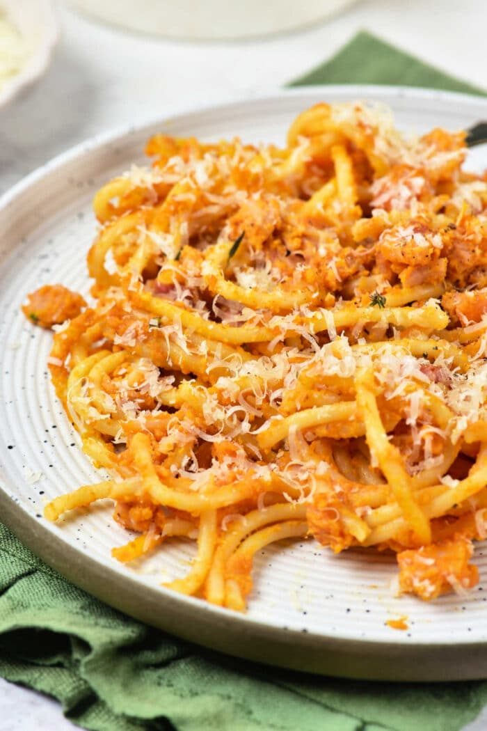 A plate of good Pumpkin Pasta with red sauce and grated cheese, placed on a green napkin.