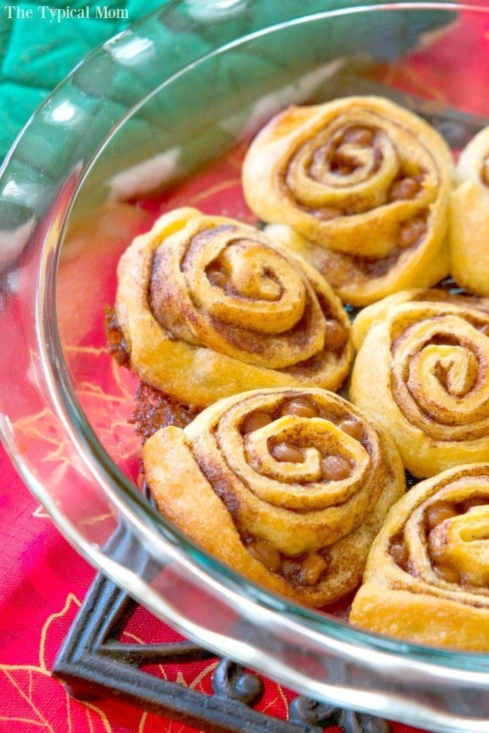 Crescent roll cinnamon rolls sit elegantly in a glass dish atop a vibrant red tablecloth.