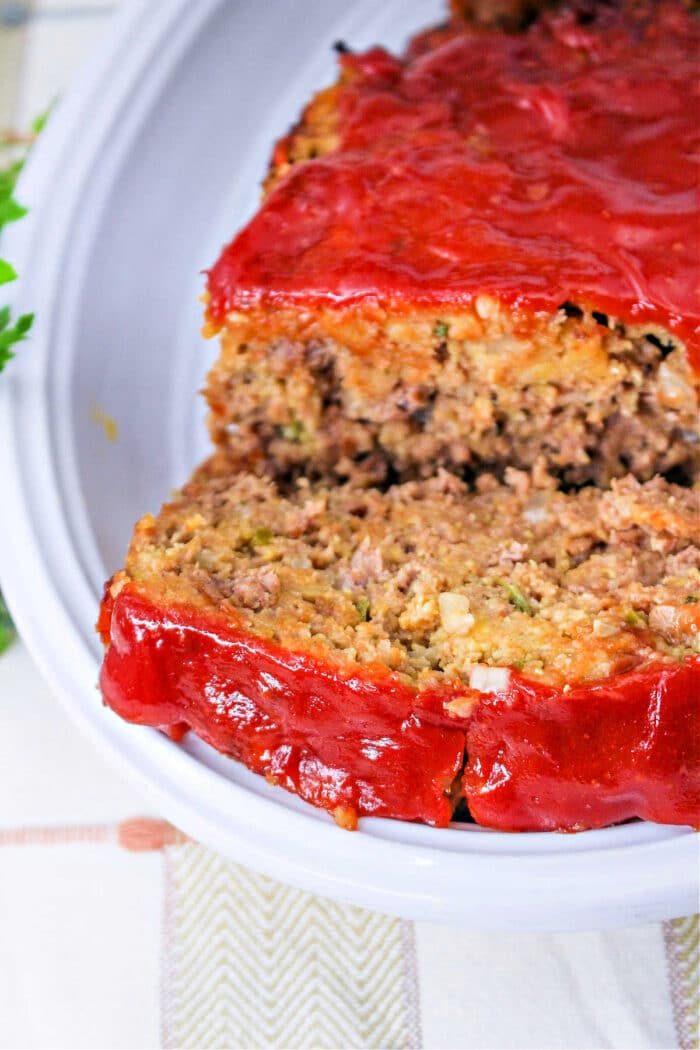 A sliced meatloaf with a thick layer of red sauce on top, served on a white plate—solid for anyone looking for a quick meatloaf recipe.