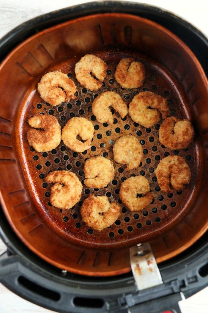 reheating shrimp in an air fryer basket, golden brown and perfectly spaced, much like when you reheat fried fish in an air fryer to achieve that crispy finish.