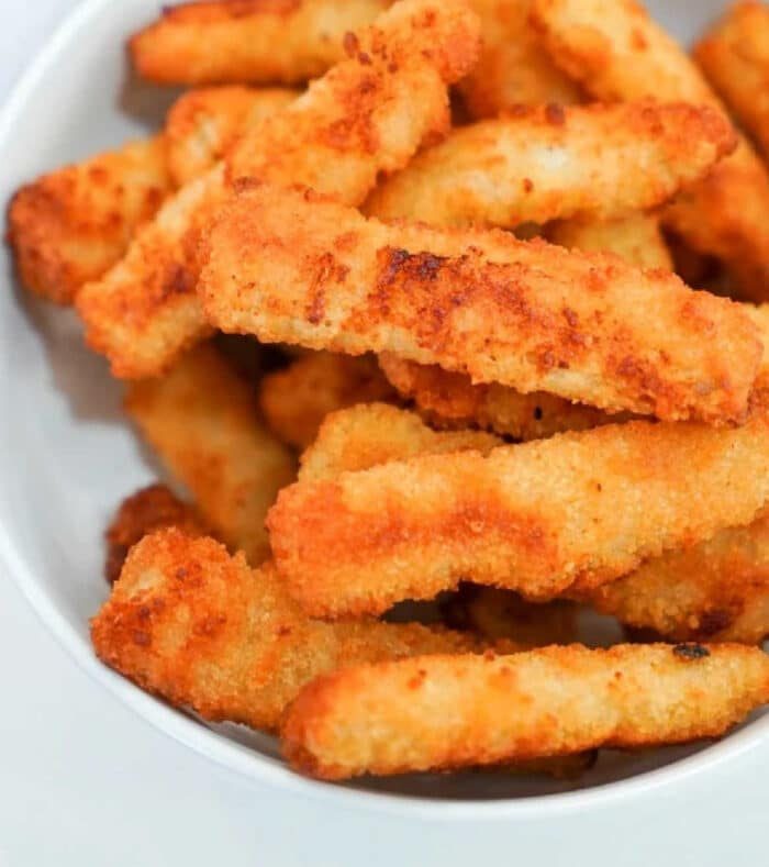 A bowl of crispy, golden-brown breaded fried fish stacked together, as irresistibly delightful as reheating fried fish in an air fryer.