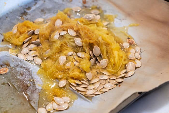 Roasted spaghetti squash seeds and pulp on parchment paper, freshly scooped