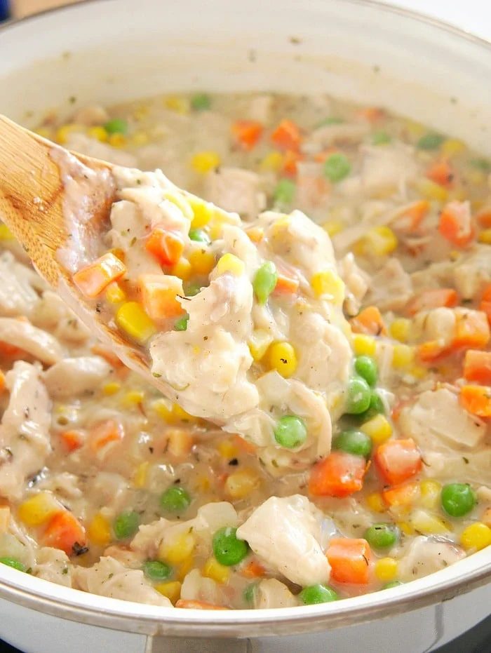 A spoonful of creamy simple chicken pot pie recipe, brimming with peas, corn, and carrots.