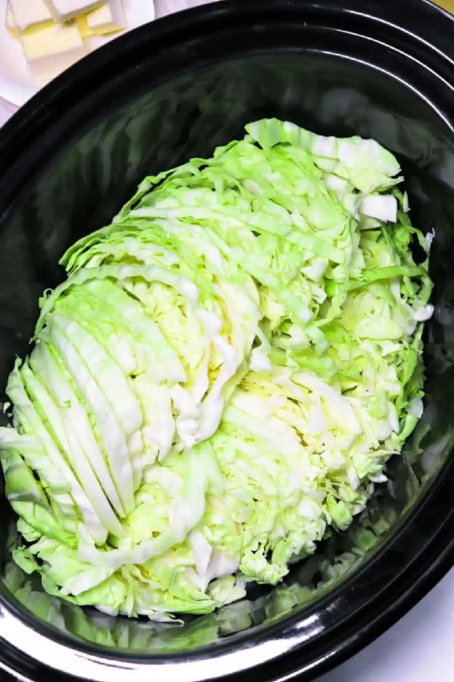 A heap of slow cooker cabbage rests inside a sleek black cooker, primed for a good transformation.
