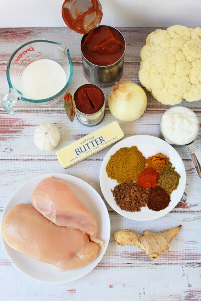 Ingredients for a good Slow Cooker Chicken Makhani dish, including chicken, spices, onion, garlic, butter, cauliflower, and tomato paste.