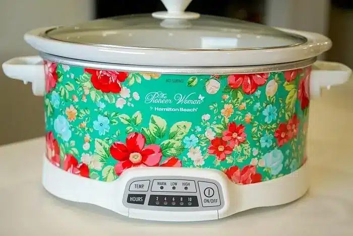A floral design slow cooker with a white base and lid sits on a kitchen countertop, solid for whipping up a 5 ingredient crockpot chili recipe.