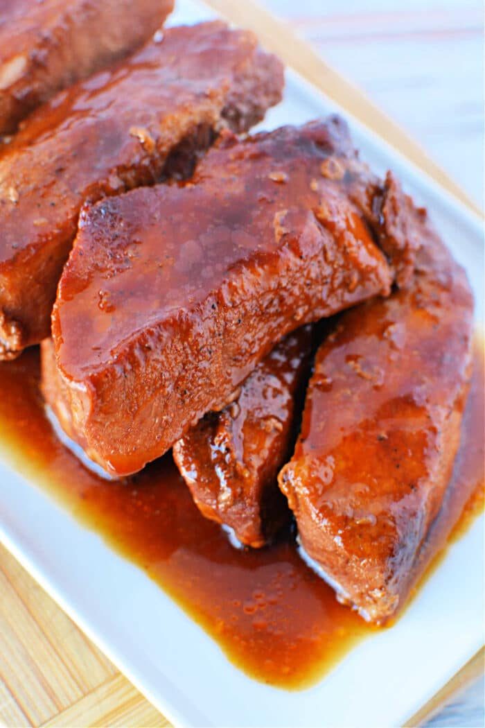 Slow cooker country-style ribs with barbecue sauce on a white platter.
