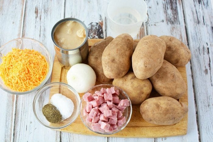 Ingredients for slow cooker scalloped potatoes: potatoes, cubed ham, shredded cheese, onion, canned soup, salt, and pepper.