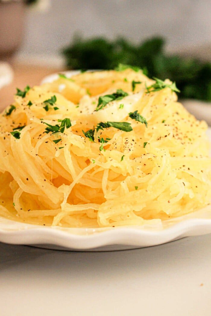 A slow cooker spaghetti squash sits on the plate, enhanced by a parsley garnish and a sprinkle of black pepper.