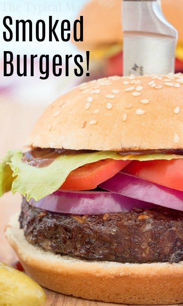 Close-up of a smoked burger with lettuce, tomato, red onion, and a sesame bun—discover our mouthwatering smoked burgers recipe! Smoked Burgers!.
