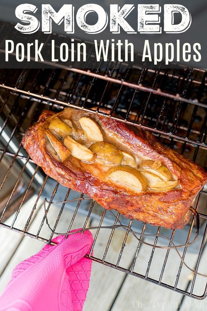 A smoked pork recipe featuring pork loin topped with apple slices on a grill rack, with a pink oven mitt holding the rack.