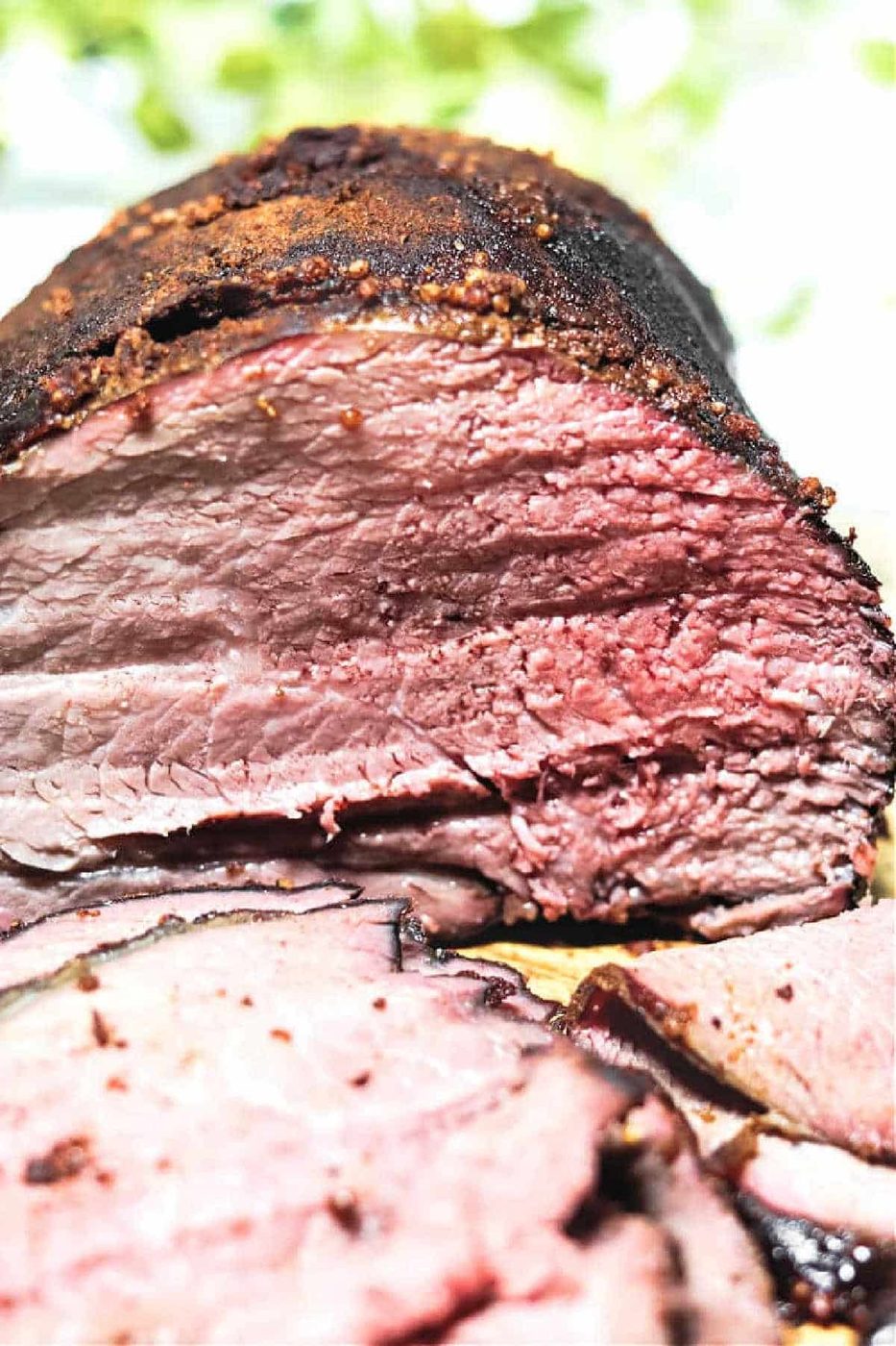 Sliced Smoked Sirloin Tip Roast displays a juicy interior and a dark, seasoned crust, like classic smoked beef brisket.
