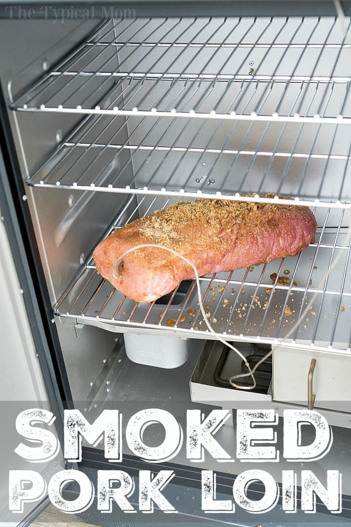 A boneless pork loin, seasoned with spices, rests inside a metal smoker on a rack. The interior boasts multiple shelves and a small pan at the bottom. The inviting words "Smoked Pork Loin" enhance the image's allure, perfectly capturing the essence of smoking this delectable dish.