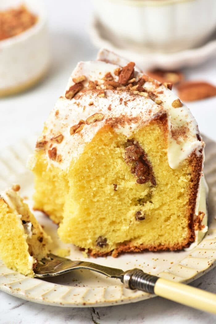 A slice of Sock it to us cake, made with a delightful cake mix, sits on a plate with frosting and nuts, accompanied by a fork.