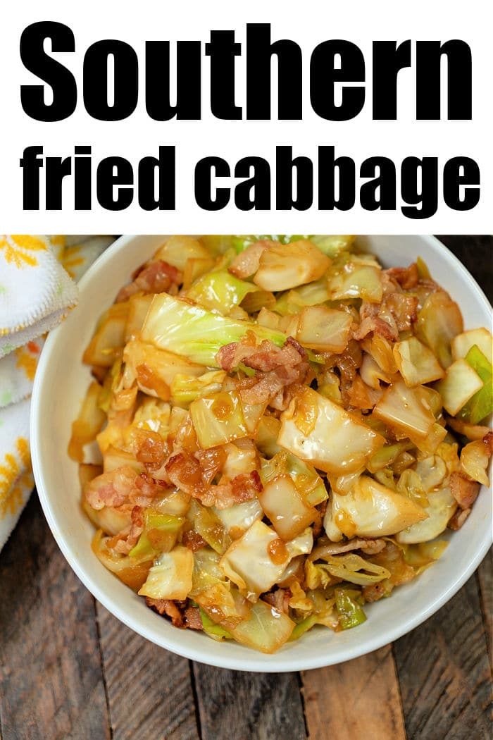 A bowl of Southern Fried Cabbage with crispy bacon sits on a wooden table, beside a white floral napkin.
