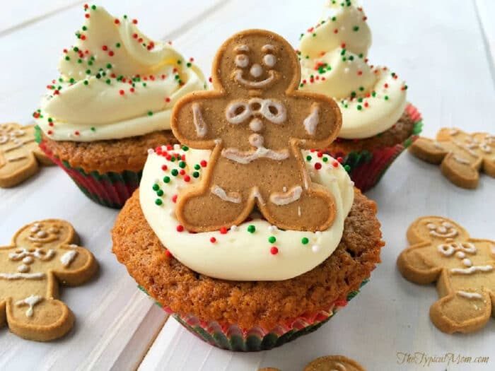 Cupcakes with white frosting, colorful sprinkles, and gingerbread man cookies on top, surrounded by more cookies—solid alongside a slice of Starbucks gingerbread loaf.