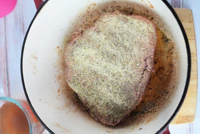 A seasoned raw meat roast sits in a pot, poised for cooking into a good stove top pot roast.