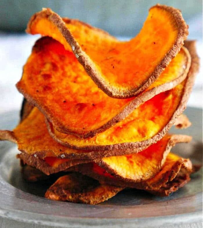 A stack of crispy, homemade sweet potato chips air fryer-style sits on a plate, perfectly golden and good.