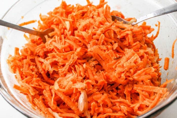 A bowl of shredded sweet potato latkes, ready for sharing. Two forks invite you to dive into this delightful spread.