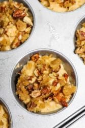 Close-up of muffin tin with unbaked sweet potato muffins topped with crumbly pecan streusel.