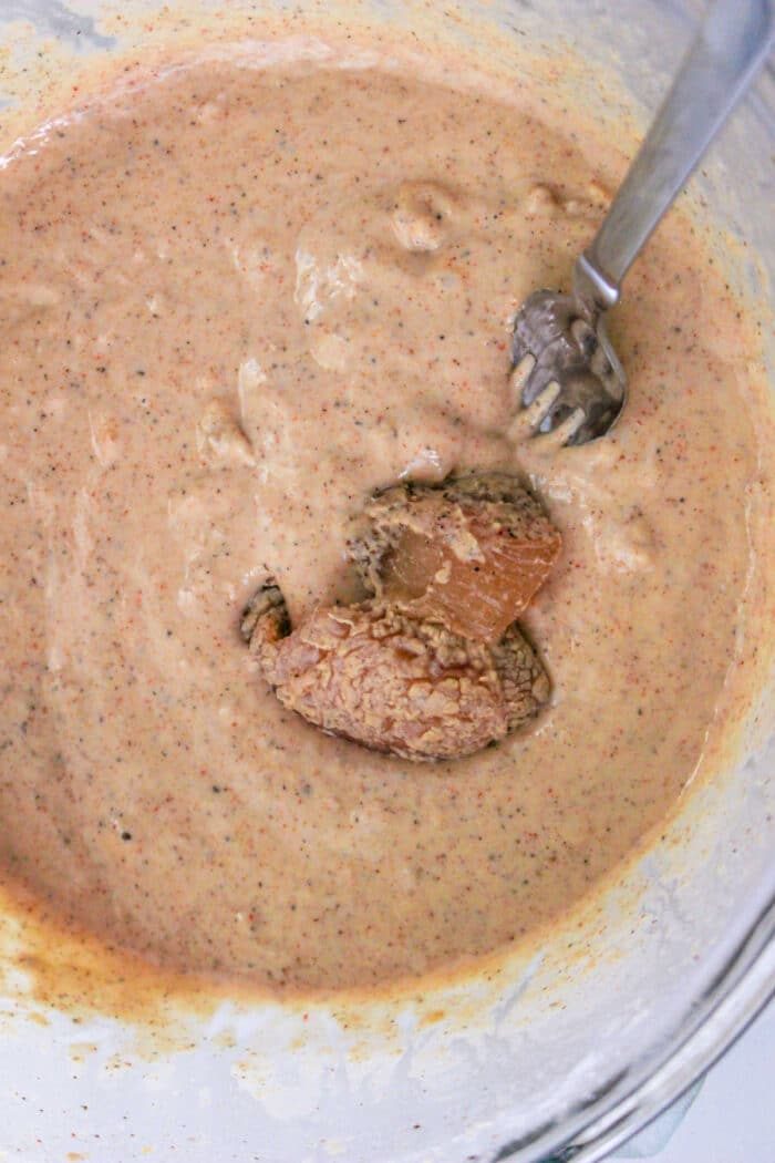 Batter in a glass bowl with a fork stirring in tempura butter, ready to coat the Chicken Nuggets.